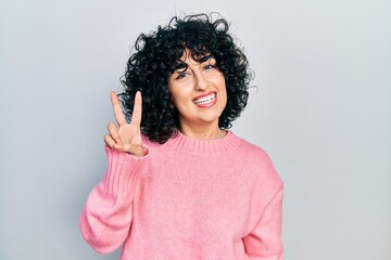 Young middle east woman wearing casual clothes smiling looking to the camera showing fingers doing victory sign. number two.