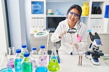 Young chinese woman wearing scientist uniform using loupe at laboratory