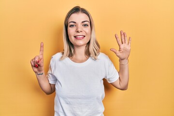 Beautiful caucasian woman wearing casual white t shirt showing and pointing up with fingers number six while smiling confident and happy.