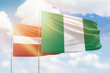 Sunny blue sky and flags of nigeria and latvia