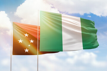 Sunny blue sky and flags of nigeria and papua new guinea