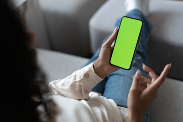 Young woman user customer hold smartphone mock up green screen in hand use mobile shopping app, check social media news