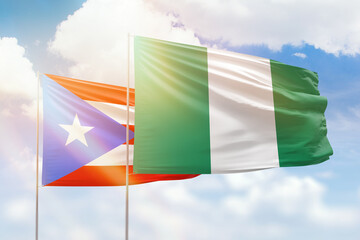 Sunny blue sky and flags of nigeria and puerto rico