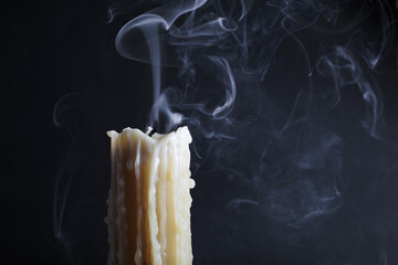 Candle with smoke on black background. Melted wax