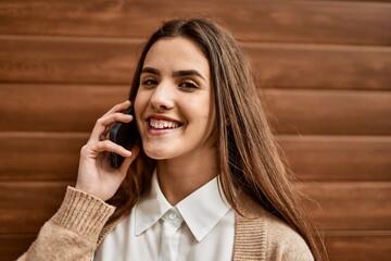 Young hispanic businesswoman smiling happy talking on the smartphone at the city.