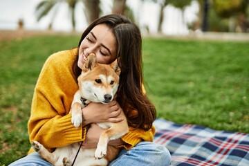 Beautiful young woman hugging happy shiba inu dog at park