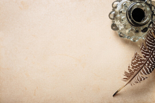 Old quill pen and vintage inkwell with old paper blank sheet