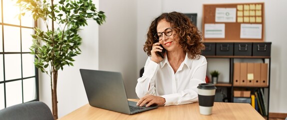 Mature hispanic woman working speaking on the phone at the office