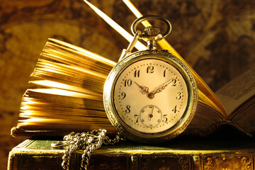 Vintage pocket watch with opened antique book. Old shabby wise books.