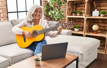 Middle age woman having online guitar class at home