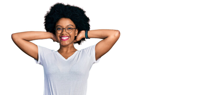 Young african american woman wearing casual white t shirt relaxing and stretching, arms and hands behind head and neck smiling happy
