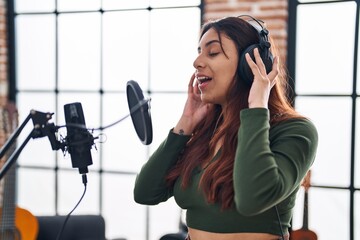 Young hispanic woman musician singing song at music studio