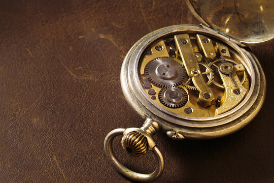 Old pocket watch. Ancient gears on the leather background