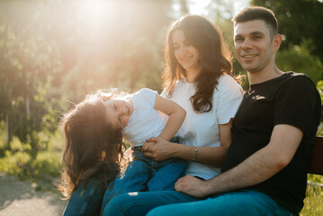 Young cheerful family with daughter having fun outdoors