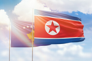 Sunny blue sky and flags of north korea and kosovo