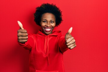Young african american woman wearing casual sweatshirt approving doing positive gesture with hand,...