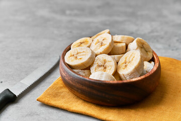 Photo of banana slices in a bowl on a concrete surface