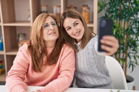 Mother and daughter making selfie by the smartphone sitting on desk at home