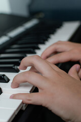 Obraz premium Fingers of a child on the piano keyboard. Close-up. Vertical