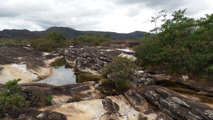 puddles of water, rocks, mountains and many plants around the slab waterfall in Milho Verde in Minas Gerais