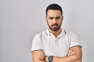 Young hispanic man with beard wearing casual clothes over white background skeptic and nervous,...