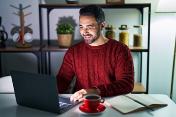 Young hispanic man with beard using computer laptop at night at home with a happy and cool smile on face. lucky person. © Krakenimages.com