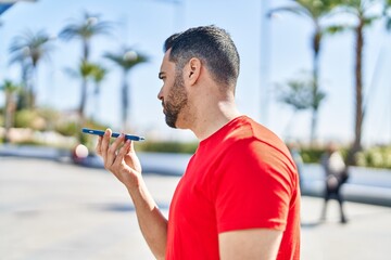 Young hispanic man talking on the smartphone at street