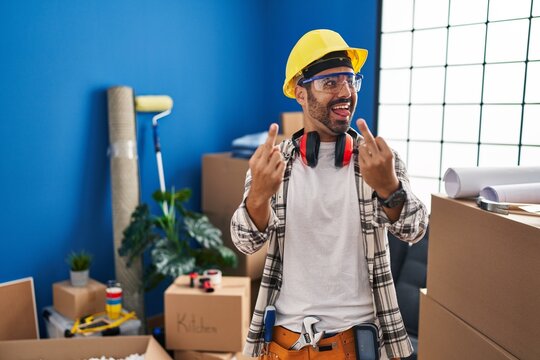 Young hispanic man with beard working at home renovation showing middle finger doing fuck you bad expression, provocation and rude attitude. screaming excited