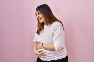 Obraz premium Pregnant woman standing over pink background with hand on stomach because indigestion, painful illness feeling unwell. ache concept.