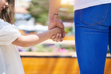 Father and daughter standing with hands together at park