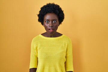Fototapeta na wymiar African young woman standing over yellow studio afraid and shocked with surprise and amazed expression, fear and excited face.