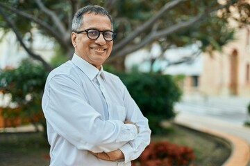 Middle age southeast asian man smiling confident with crossed arms by the park