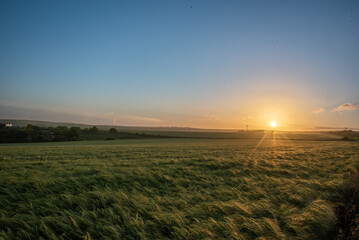 Fototapeta na wymiar Farm field in sunset colours and cloudy skies