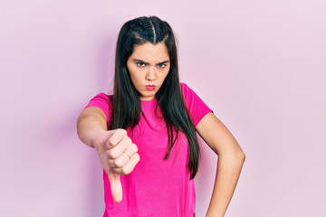 Fototapeta premium Young hispanic girl wearing casual pink t shirt looking unhappy and angry showing rejection and negative with thumbs down gesture. bad expression.