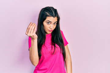 Young hispanic girl wearing casual pink t shirt doing italian gesture with hand and fingers confident expression