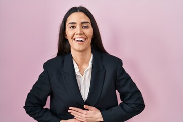 Young brunette woman wearing business style over pink background smiling and laughing hard out loud because funny crazy joke with hands on body.