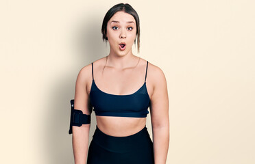Young hispanic woman wearing sportswear afraid and shocked with surprise expression, fear and excited face.