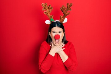 Young hispanic woman wearing deer christmas hat and red nose shouting suffocate because painful strangle. health problem. asphyxiate and suicide concept.