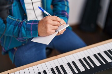 Young chinese man singer composing song at music studio