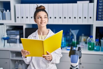 Adorable girl scientist reading book studying at laboratory
