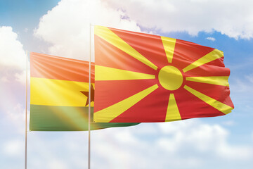 Sunny blue sky and flags of north macedonia and ghana