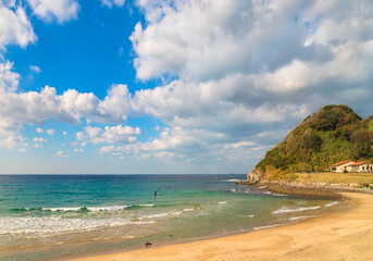 Japanese surfer making standup paddleboarding sport in the sea along the beach of the Sakurai Futamigaura's Couple Stones in Fukuoka.