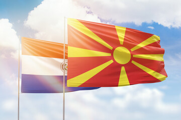 Sunny blue sky and flags of north macedonia and paraguay