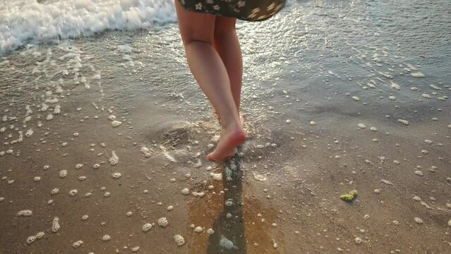 Woman legs in sea water. Carefree happy girl enjoys summer at the beach, jumping at seaside. Travel, vacation, summer concept.