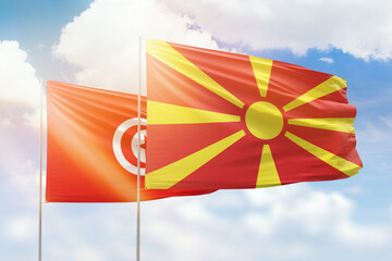 Sunny blue sky and flags of north macedonia and tunisia