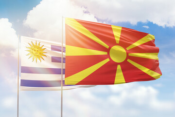 Sunny blue sky and flags of north macedonia and uruguay