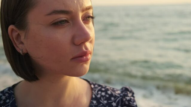 Beautiful woman looking on sea horizon at sunrise. Happy girl on the beach enjoying peaceful summer vacation.
