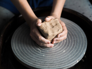 Ceramist young woman preparing clay to make pottery pieces in her studio; anonymous hands at work....