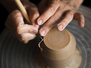 Ceramist at work using tools for creating handmade vase in studio, selective focus. Close up of...