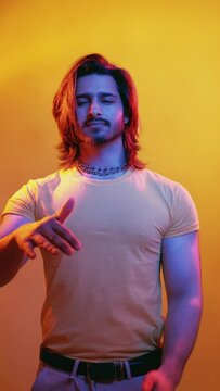 So-so gesture. Disappointed man. Neon light portrait. Bad choice. Skeptic handsome guy waving palm hand in blue red vibrant color glow isolated orange vertical.